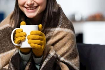 Woman snuggled in blanket drinking hot cocoa